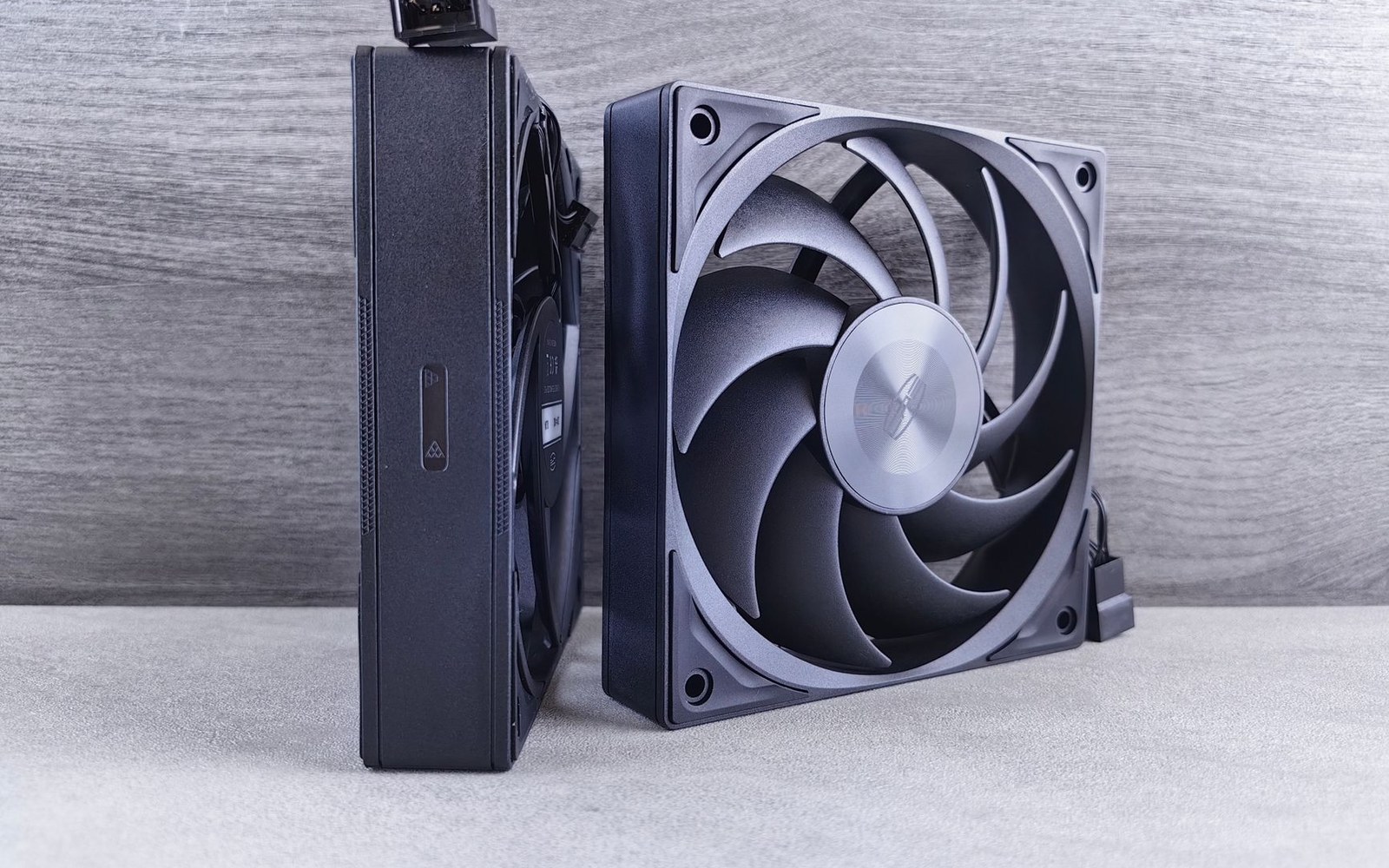 Two computer case fans stand upright side by side, one shown edge-on and one face-on